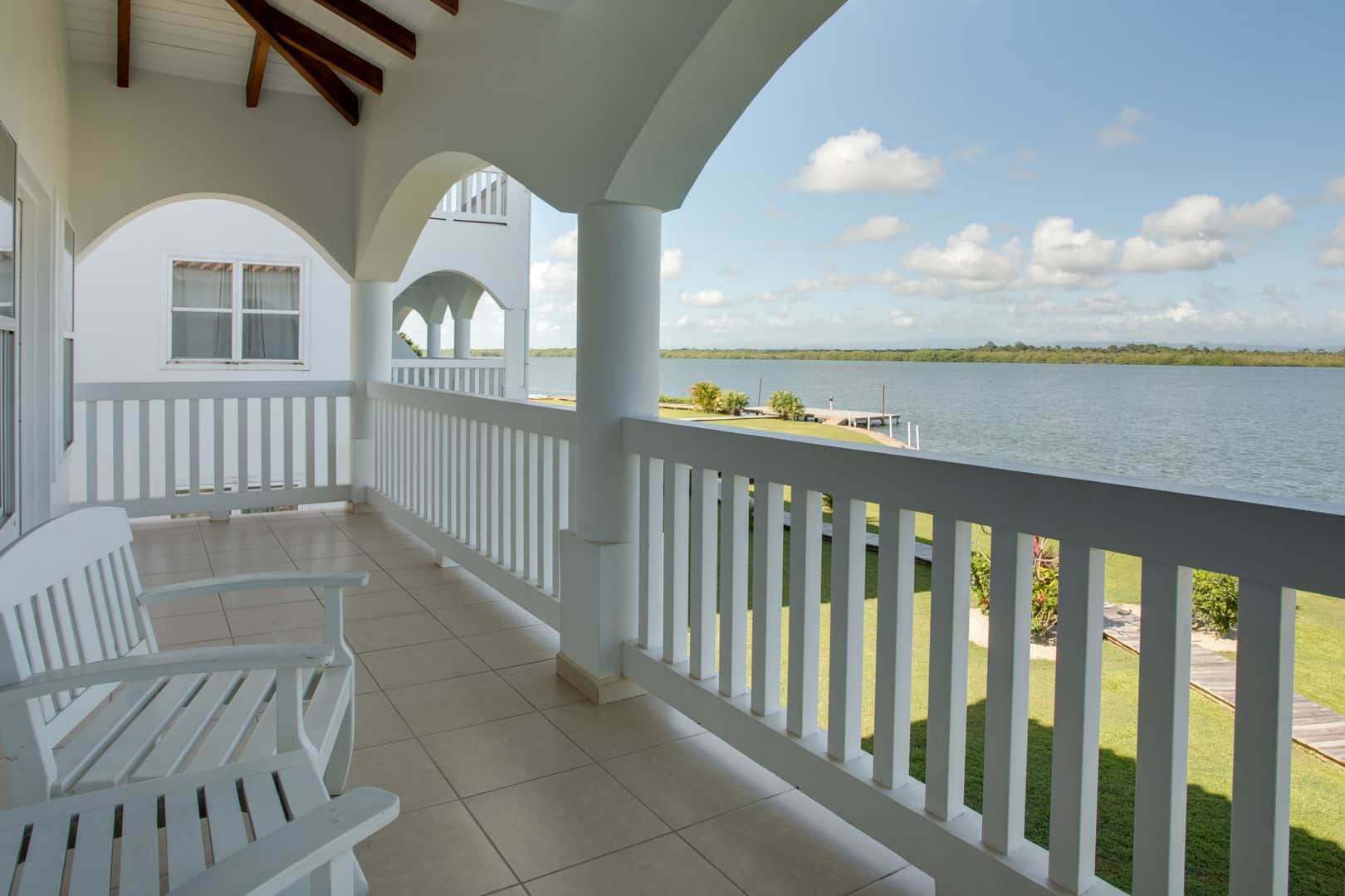 Balcony with two white wooden chairs a view of the lagoon outside of the 2 Bedroom Lagoon Bayview at Umaya Resort & Adventure