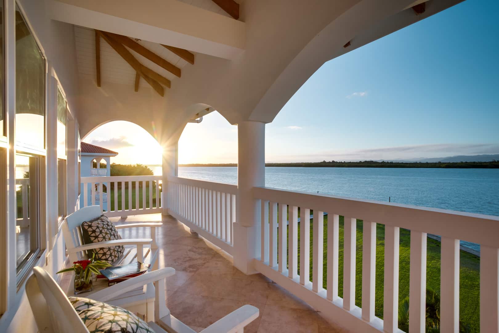 A balcony with two white wooden chairs with a view of the lagoon outside of the 1 Bedroom Beachfront at Umaya Resort & Adventure