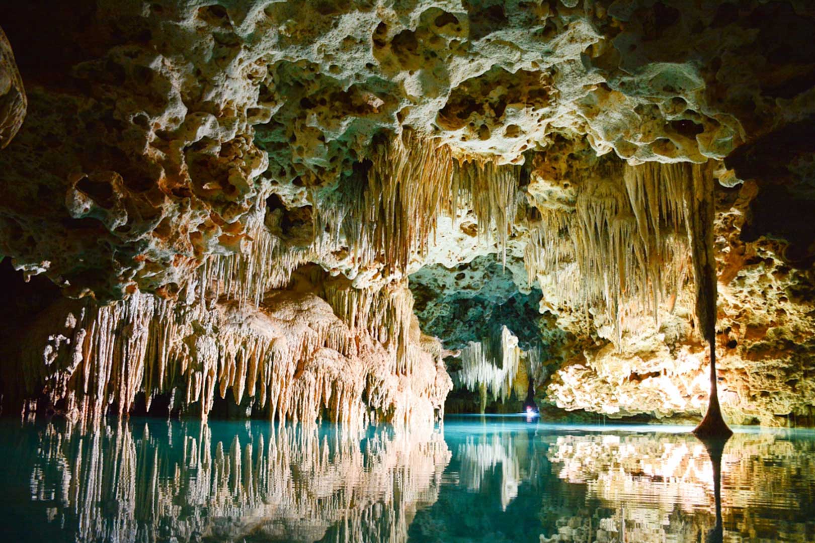 Cave ceiling with stalactites and clear blue water inside the Actun Tunichil Muknal (ATM Cave) at The Rainforest Lodge at Sleeping Giant Resort