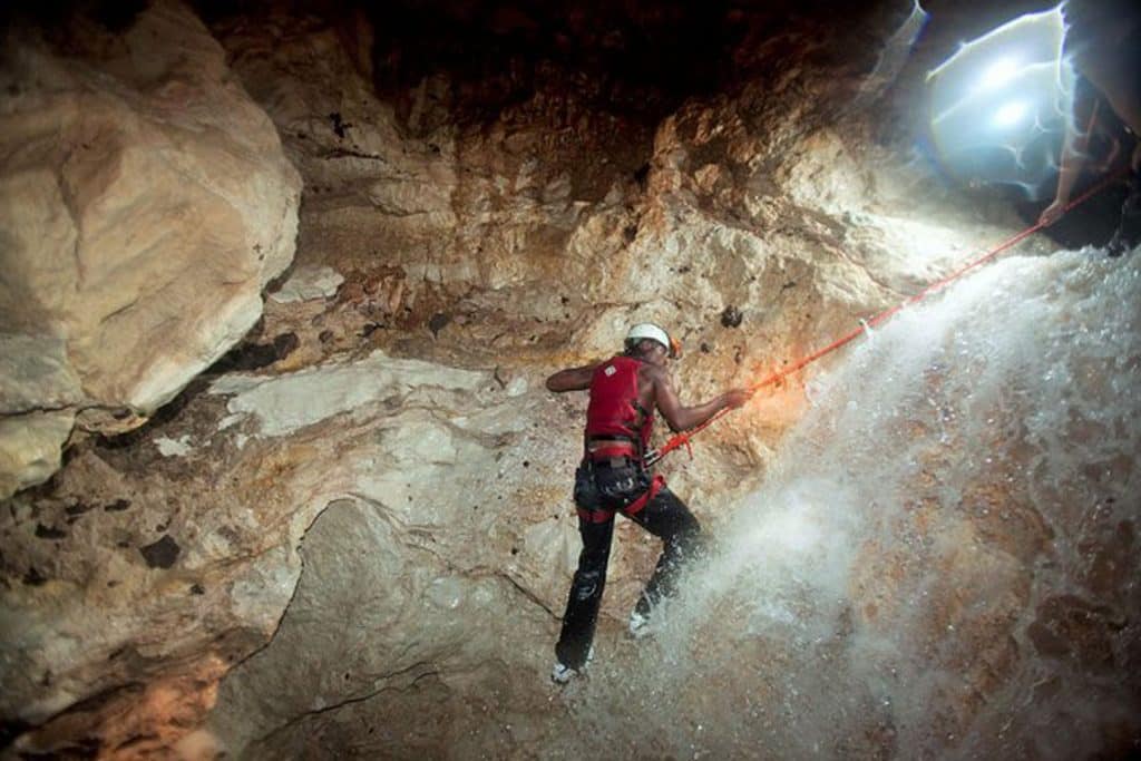 A guest doing the waterfall cave expedition at the Rainforest Lodge at Sleeping Giant Resort