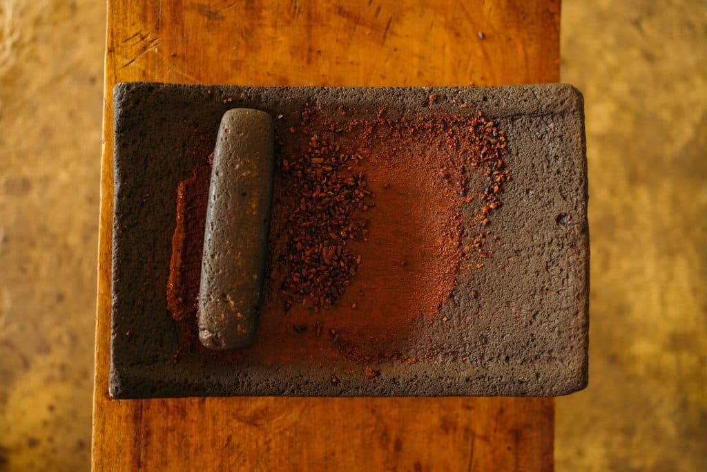 Cocoa seeds being ground with a traditional mortar and pestle in the Maya Chocolate Tour at The Lodge at Jaguar Reef