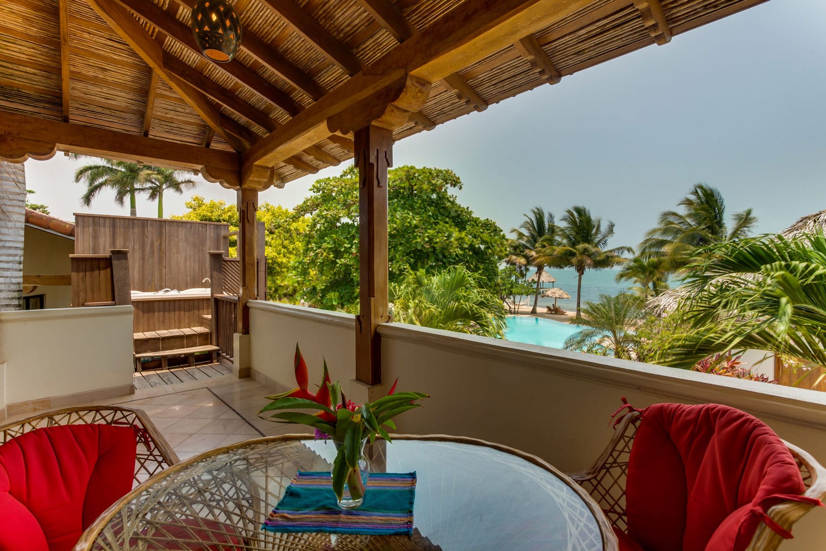 Front balcony with a glass table and two wooden chairs outside of the Seaview Deluxe Rooms at The Resort at Almond Beach