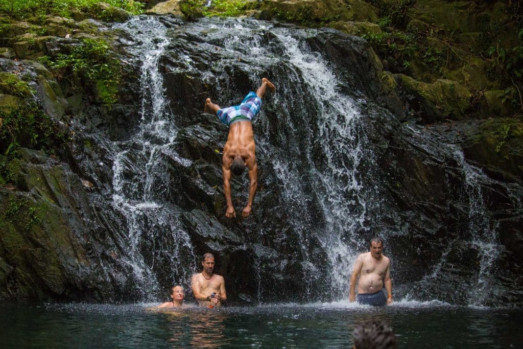 A guest diving into the waterfall at the Jaguar Preserve Waterfall Hike at The Lodge at Jaguar Reef