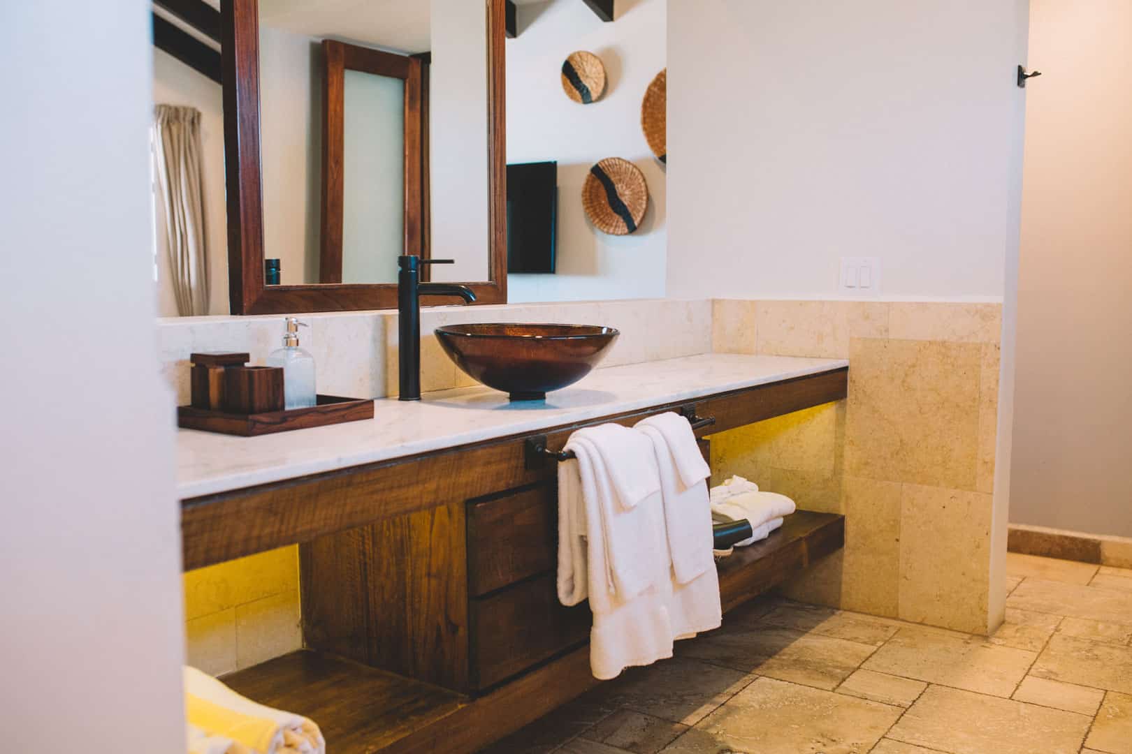 Bathroom with large white counter, a vanity mirror and brown glass sink inside of the Deluxe Suite Upper Level with Plunge Pool at The Lodge at Jaguar Reef Resort