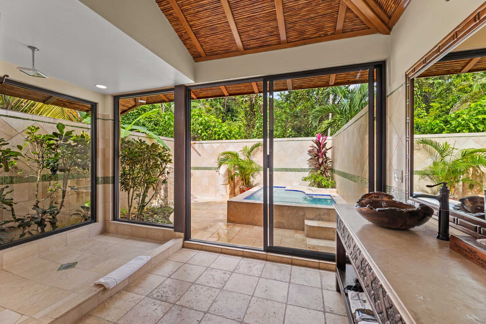 A view of the bathroom looking out through the glass doors to the plunge pool at the Jungle Cottage with Plunge Pool at The Rainforest Lodge at Sleeping Giant Resort