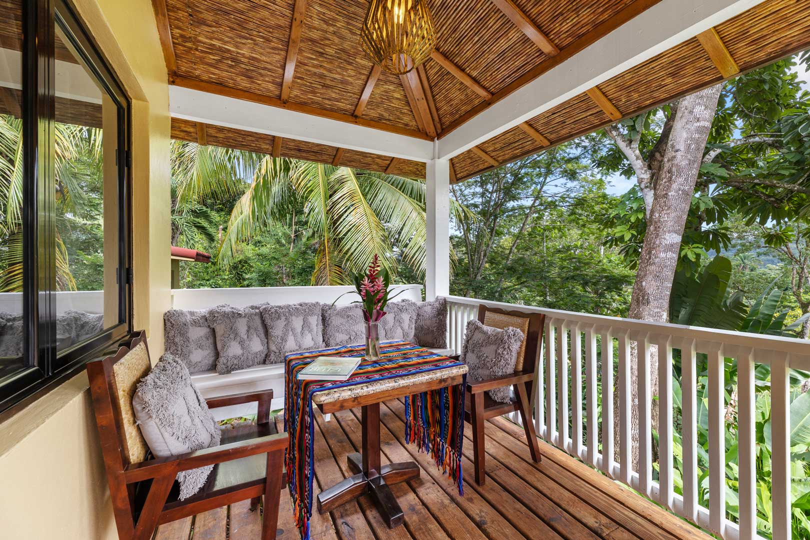 The outside balcony showing a table with chairs outside of the Jungle Cottage with Plunge Pool at The Rainforest Lodge at Sleeping Giant Resort