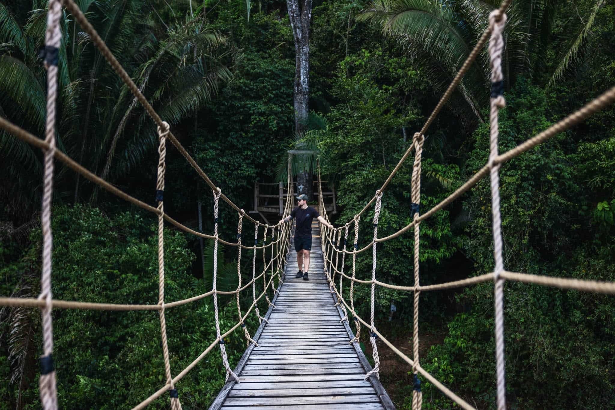 Guest walking across a jungle rope bridge at Sleeping Giant Rainforest Lodge, Sibun River Valley, Cayo District, Belize