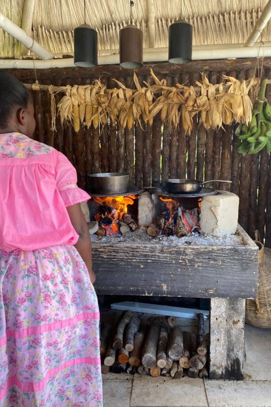 A garinagu woman monitoring two pots on the fire hearth during the Garifuna Cooking Class at The Lodge at Jaguar Reef