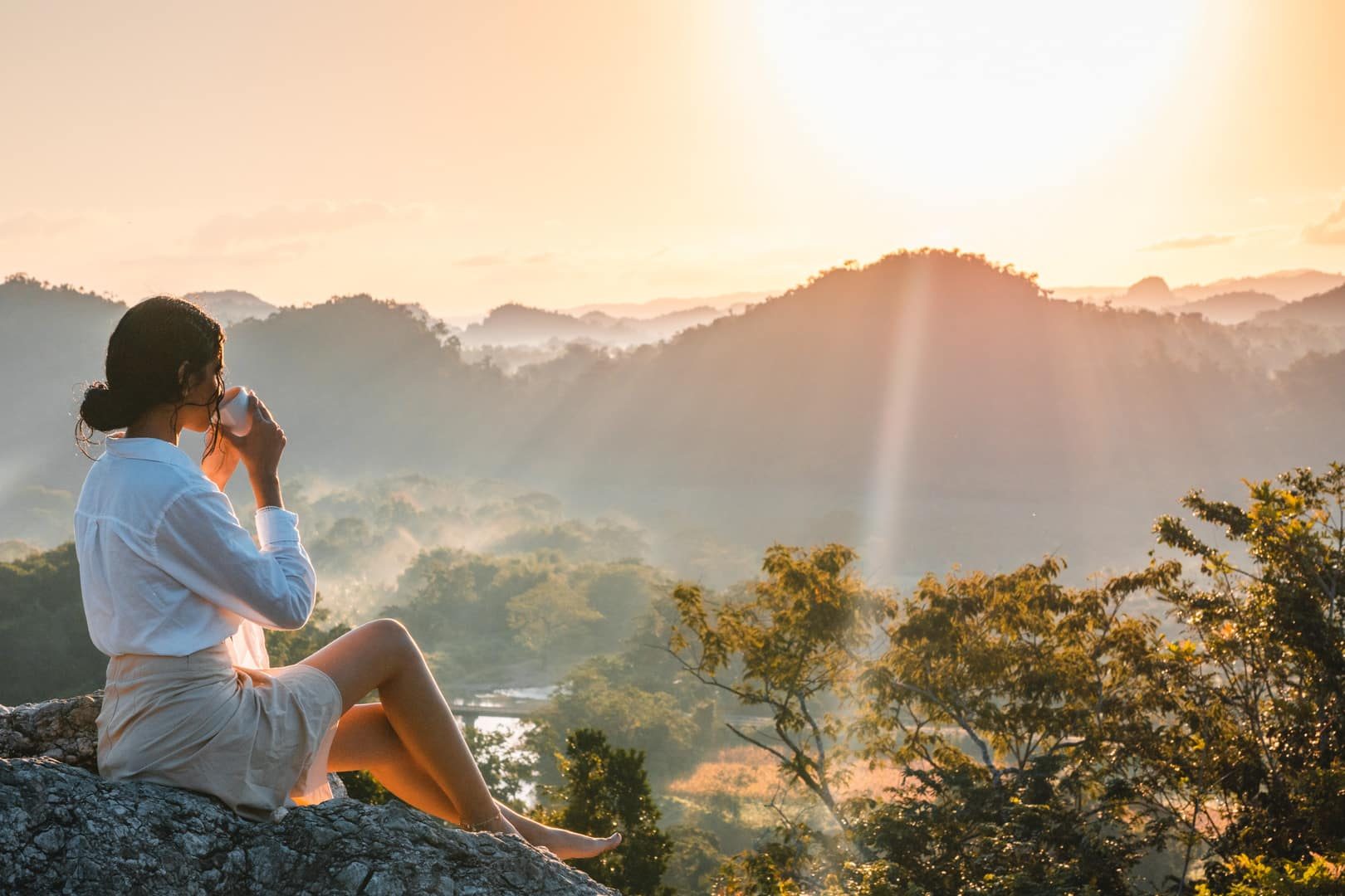 A guest in a bathrobe sipping a cup of warm tea while watching the sunrise.